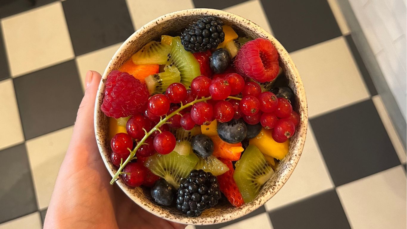 Kleurrijke fruitsalade met verse bessen, kiwi en mango in een handgemaakte kom